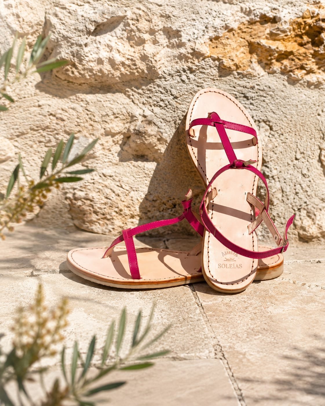 Sandales en cuir rose framboise Atelier Soleïas posées sur la pierre provençale